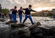 Escolares cruzan el río Rímac sobre piedras para llegar al colegio en Chosica